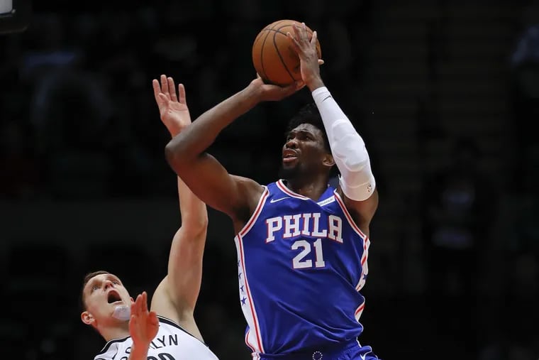 Joel Embiid (21) shoots against the Nets while defended by center Timofey Mozgov.