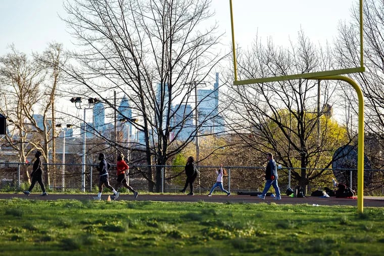 Runners, walkers and exercisers maintain social distancing as they circle the track at Thomas A. Edison High School in North Philadelphia April 6, 2020.