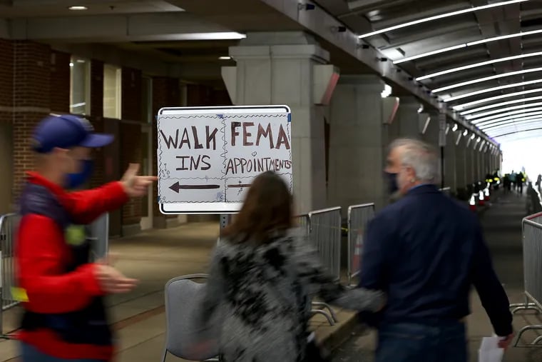 A FEMA worker directs visitors outside FEMA's mass vaccination clinic at the Pennsylvania Convention Center.