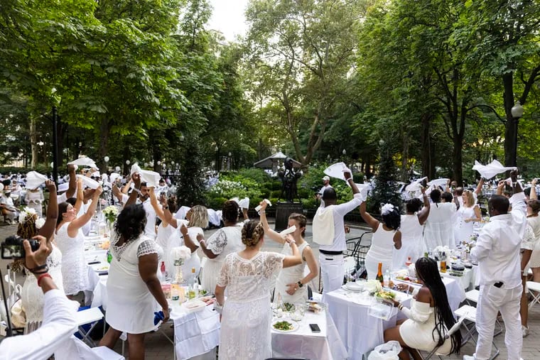 People wave their napkins in the air as a tradition to let guest know they are all set and ready to enjoy the night of the annual Diner en Blanc at Rittenhouse Square Park in Philadelphia, Pa., on Thursday, Aug., 12, 2021. 
