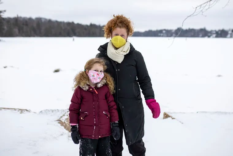 Caroline Goldrick and her daughter Edith, 6, by the frozen lake in Eagles Mere, Pa., on Wednesday, Jan. 27, 2021. Goldrick and her family moved out to Eagles Mere last year late June to escape the pandemic in the city.