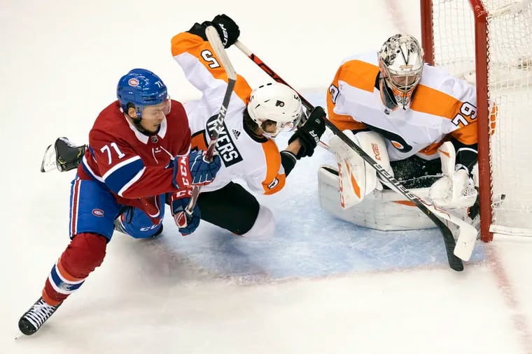 Montreal center Jake Evans (71) tries to get through Flyers defenseman Phil Myers (5) while chasing the puck in front of goaltender Carter Hart in Philly's series-clinching 3-2 win Friday.