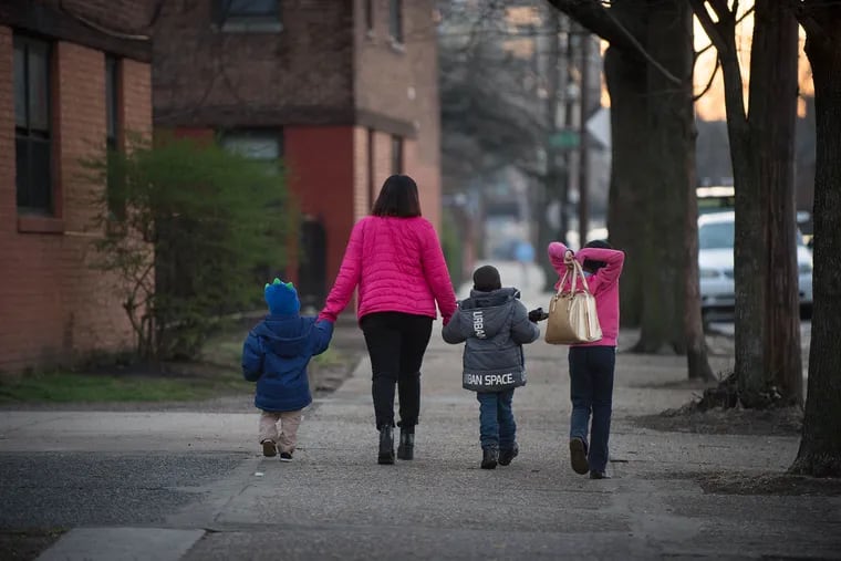 (From left) Quran Sanders, 2, Brandy Price, Khaliff Young, 5, and Sumyah Price, 8, walk home together after spending an evening at Helping Hand Rescue Mission in Philadelphia on Tuesday, March 15, 2016.  Price recently obtained her GED with the help of tutors at Helping Hand. (TRACIE VAN AUKEN/ For the Inquirer)