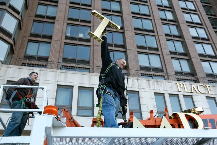 FILE- In this March 16, 2016, file photo, one of the workmen holds up the letter "T" as they remove the letters from a building formerly known as Trump Place in New York. Owners of the last of six luxury New York City condominiums that once displayed the president's name have voted to have name removed from the building. On Friday, Feb. 22, 2019, apartment owners got an email from the board of managers of a high-rise on Manhattan's west side confirming that "Trump Place" will disappear from the facade.