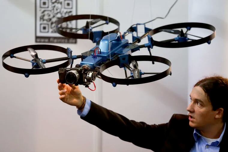 An exhibitor adjusts a Sony Corp. digital camera mounted to a drone, developed by Flairics GmbH & Co., at the Commercial Unmanned Aerial Vehicle show in London. Last month's decision to approve drones for filming movies in the United States may create opportunities for other industries, from crop dusting to mapmaking, that see value in unmanned aircraft.