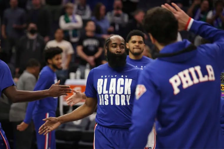 Philadelphia 76ers guard James Harden, center, greets teammates after being announced at the start of an NBA basketball game against the Minnesota Timberwolves, Friday, Feb. 25, 2022, in Minneapolis. (AP Photo/Stacy Bengs)