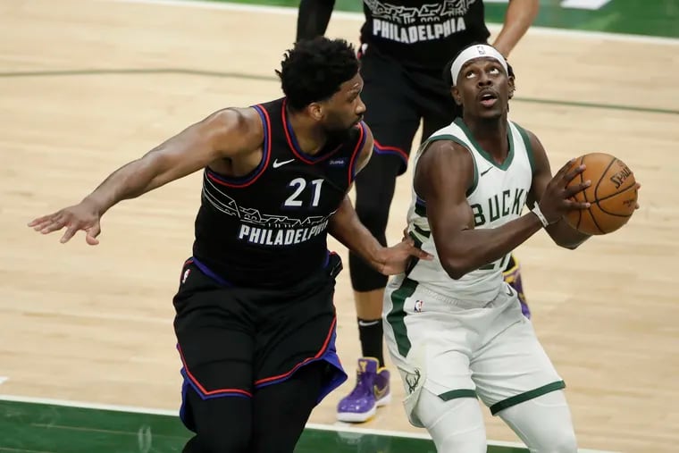 The Bucks' Jrue Holiday drives to the basket against Sixers center Joel Embiid during the first half.