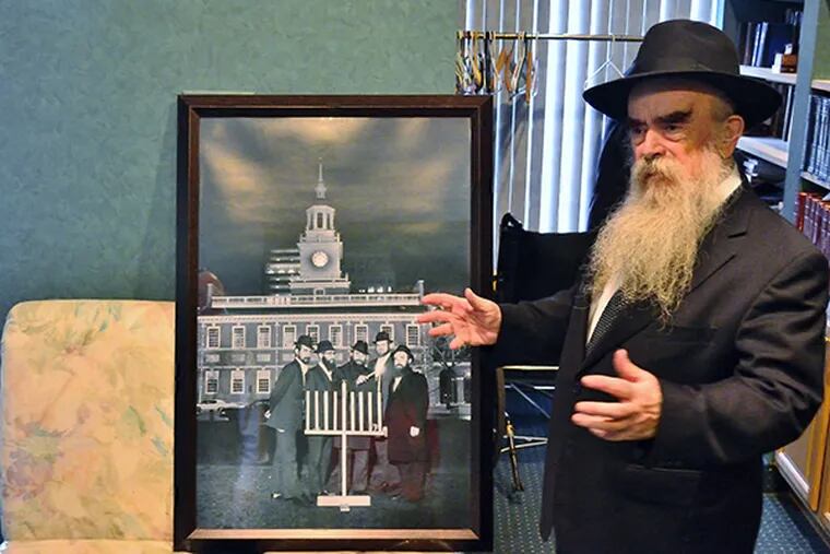 Rabbi Abraham Shemtov, head of the local Lubavitcher sect of hasidic Judaism, talks about a picture of the first official menorah on Independence Mall.  (C.F. Sanchez / Staff Photographer)