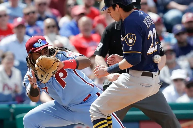 Brewers Christian Yelich gets hit by the baseball reaching third base after stealing second base on a throwing error against Phillies third baseman Maikel Franco.
