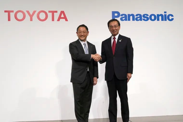 FILE - In this Dec. 13, 2017, file photo, Toyota Motor Corp. president Akio Toyoda (left) and Panasonic Corp. president Kazuhiro Tsuga pose for photographers after a joint news conference in Tokyo.