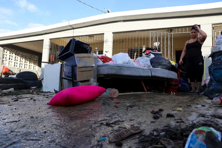 A woman looks at her water-damaged belongings after flooding caused by Hurricane Fiona tore through her home in Toa Baja, Puerto Rico.