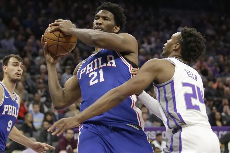 Sixers’ center Joel Embiid grabs a rebound next to Sacramento Kings guard Buddy Hield on Thursday.