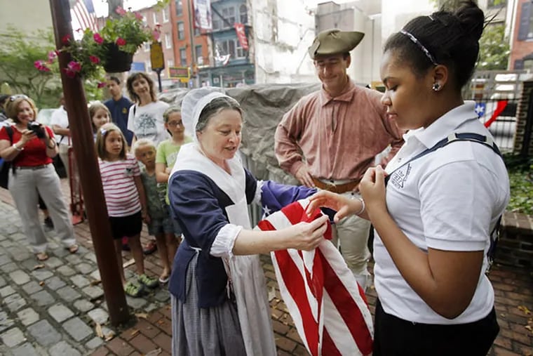 At the Betsy Ross House on Arch Street, "Betsy Ross" gives a corner of the American flag to Deneah Keller of the Preparatory Charter School in South Philadelphia. Keller helped raise the flag as part of Flag Day ceremonies.