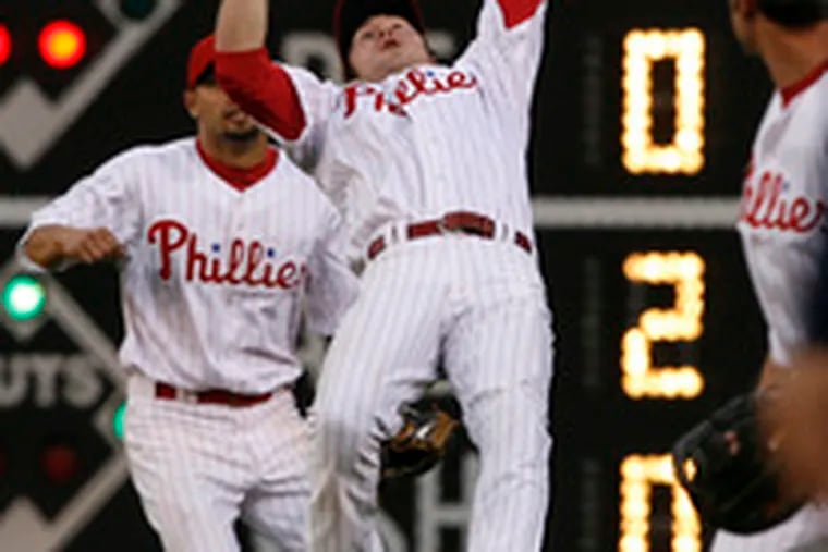 Chase Utley makes the adjustment - and the catch - on a wind-carried fly by Bill Hall in the third inning at Citizens Bank Park. Shane Victorino, who had misplayed a fly earlier, closed in from right field.