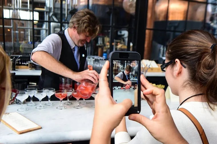 Jack Falkenback, a bartender at Philadelphia Distilling, is photographed by a member of the Association of Food Journalists as he makes drinks.