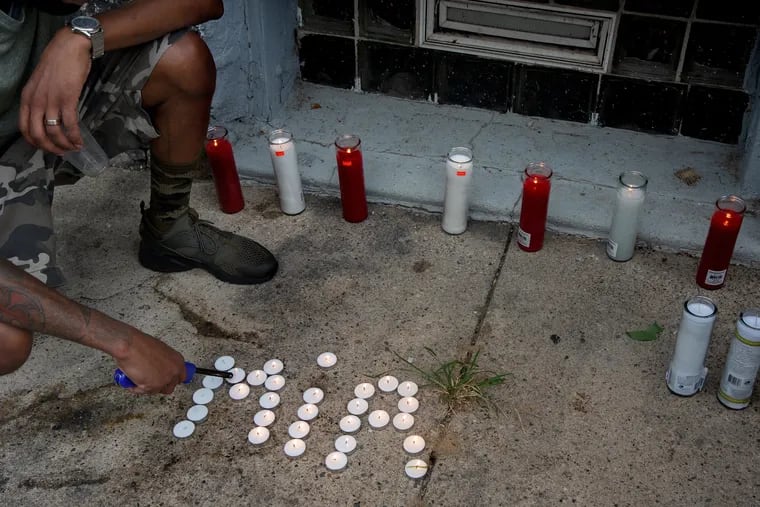 A neighbor on North Simpson Street in West Philadelphia prepares for a candlelight vigil for 7 year-old Zamar Jones last week. Sometimes called "Mir" for short, Jones died earlier in the day after being shot while playing on his front porch.