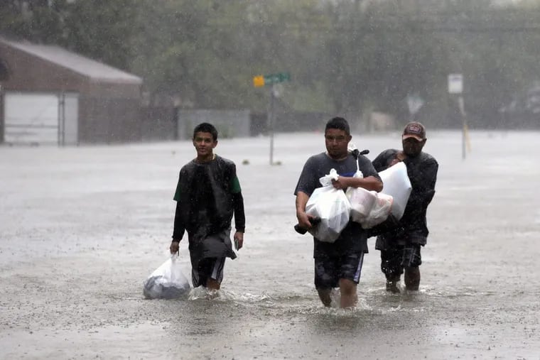 Jose Beltran (center) makes his way out of his flooded neighborhood with nephew Jonathan Beltran (left) and Abram Gutierrez.