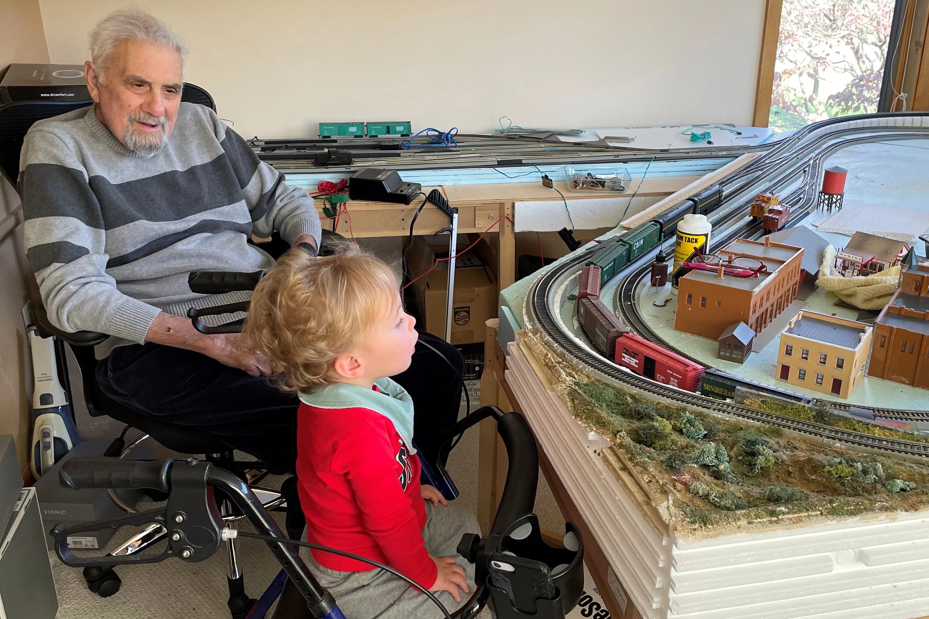 A model train enthusiast, Dr. DeCosmo watches as his great-grandson takes in one of his recent layouts.