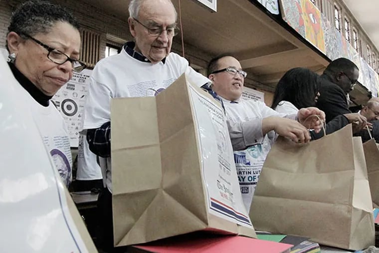 (Left to right) Volunteers Sharmain Matlock-Turner, Pres of Urban Affairs Coalition, Senator Harris Wofford and Phila. Councilman at Large David Oh fill bags with school supplies in fast assembly line fashion during the Martin Luther King Day event and celebration at Girard College in Philadelphia on January 20, 2014. ( ELIZABETH ROBERTSON / Staff Photographer )