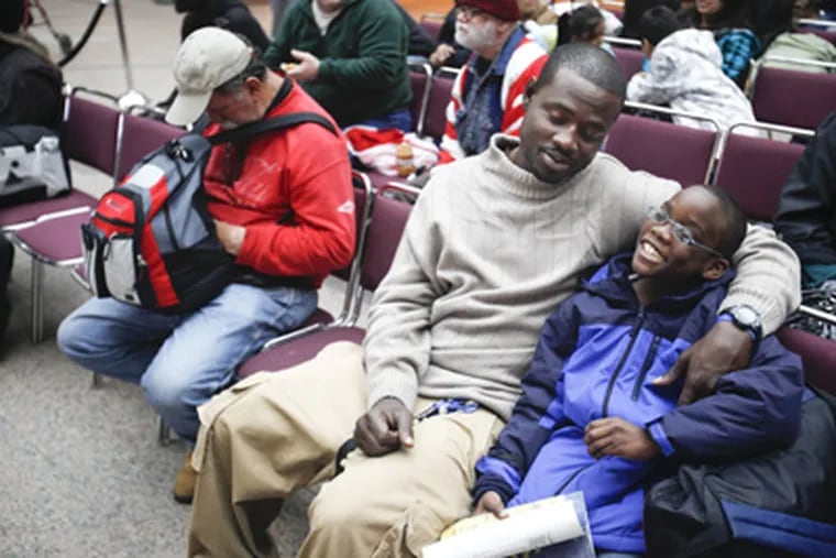 John Williams (left) and his son, Amarion Hood (right) wait at  Atlantic City Convention Center for an evacuation bus as Hurricane Sandy approaches on Sunday. (Michael S. Wirtz / Staff Photographer)