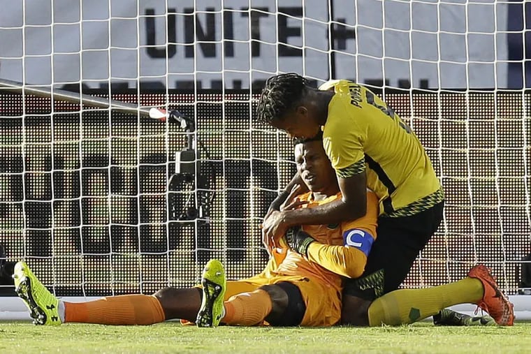 Jamaica goalkeeper Andre Blake, bottom, is consoled by Alvas Powell after being injured during the first half of the Gold Cup final soccer match against the United States in Santa Clara, Calif.