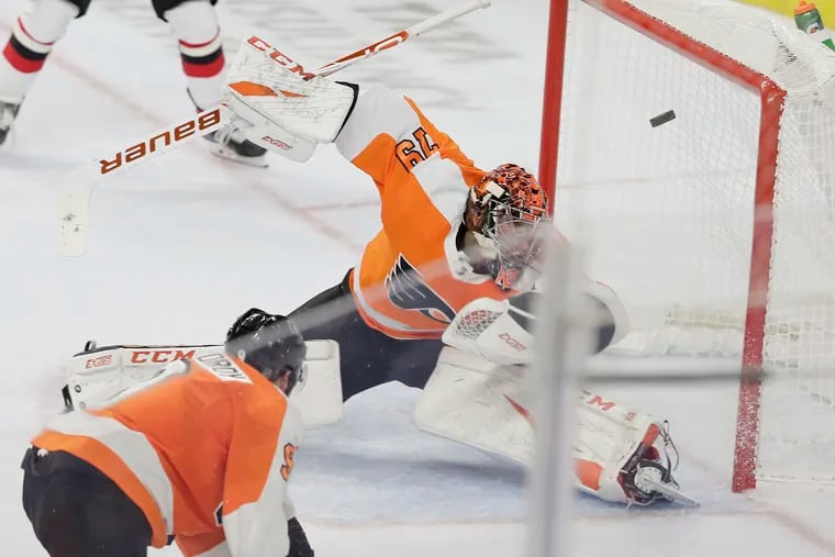 Goalie Carter Hart somehow swats this shot away during a Devils power play that saw the Flyers two men down in the second period Wednesday.