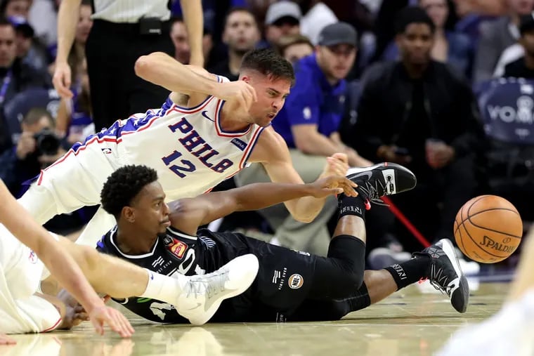 T.J. McConnell, top,  of the Sixers dives after a loose ball against Casper Ware, Jr. of Melbourne United in the 4th quarter of a exhibition game at the Wells Fargo Center on Sept. 28, 2018.