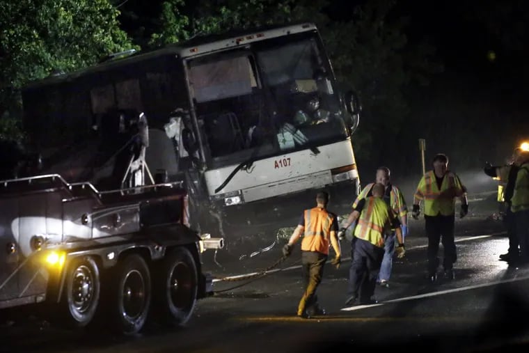Crews work to pull the overturned tour bus out of the woods after it collided with a tractor trailer in the southbound lanes of the N.J. Turnpike in West Deptford just after 12:30 a.m. on May 26, 2017.
