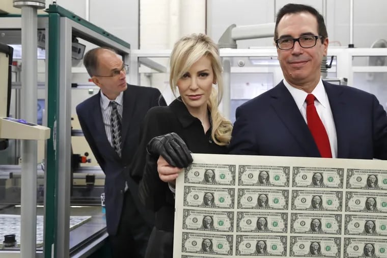 Treasury Secretary Steven Mnuchin, right, and his wife Louise Linton, hold up a sheet of new $1 bills, the first currency notes bearing his signature, Wednesday, Nov. 15, 2017, at the Bureau of Engraving and Printing (BEP) in Washington. (AP Photo/Jacquelyn Martin)