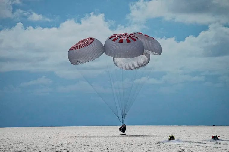 The capsule carrying SpaceX's crew parachutes into the Atlantic Ocean off the Florida coast on Saturday.