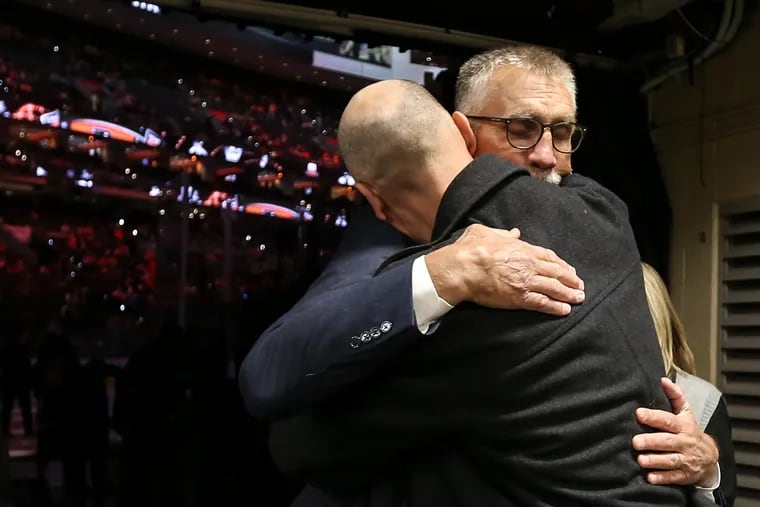 At the Hall of Fame ceremonies, inductee Paul Holmgren (background) gets a hug from his son Wes at the Wells Fargo Center.