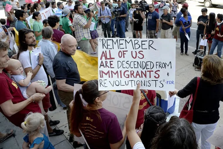 A group of about 100 pro-immigrant demonstrators gather views in a counter-protest against a group of Tea Party protesters Friday. The Tea Partiers were staging a rally against the surge in illegal immigration in front of The Bourse Building. (Clem Murray / Staff Photographer)