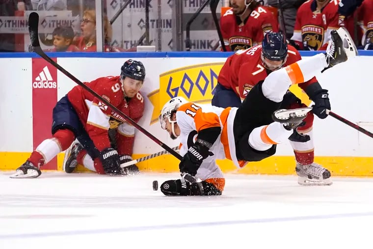 Flyers right wing Travis Konecny falls as he goes for the puck against Florida Panthers center Sam Bennett (9) and defenseman Radko Gudas (7) during the first period.