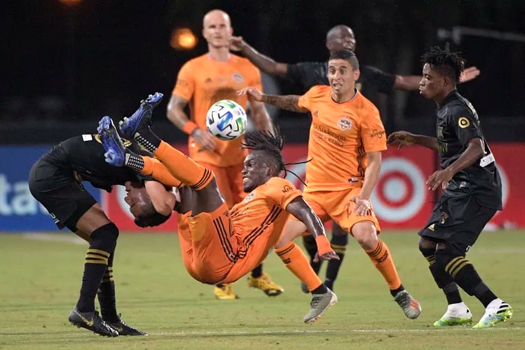 Houston Dynamo forward Alberth Elis (7) falls over Los Angeles FC midfielder Eduard Atuesta, left, while fighting for a header during the first half.