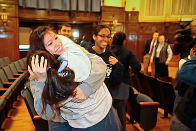 Theresa Ta, 16, shares a hug with her sister Odile, a senior, in the auditorium after hearing that West Catholic High School will remain open.