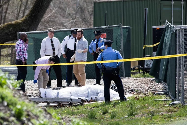 Police and medical examiners survey a body that was found wrapped in a tarp in a parking lot off Martin Luther King Jr. Blvd near Black Road on Friday. SYDNEY SCHAEFER / Staff Photographer