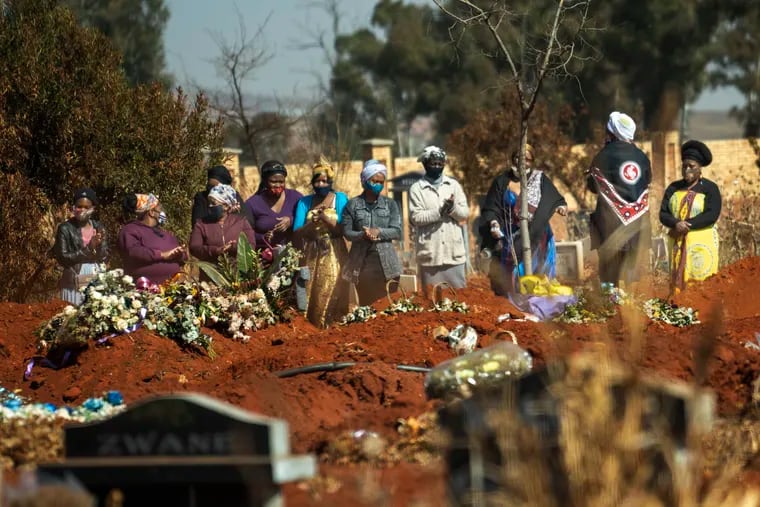 Mourners pray during a burial ceremony at the Olifantsveil Cemetery outside Johannesburg, South Africa.