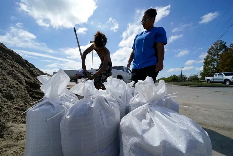 Stephanie Verrett and Jodie Jones fill sandbags to protect their home in anticipation of Hurricane Delta, in Houma, La.