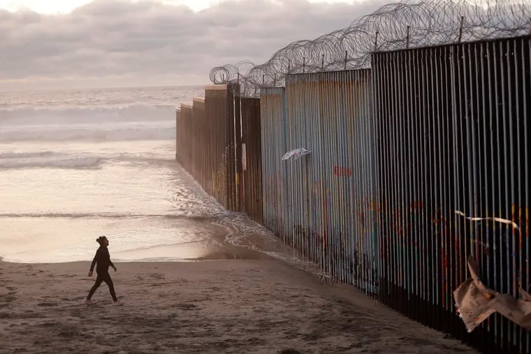 In January, a woman was pictured walking on the beach next to a border wall topped with razor wire in Tijuana, Mexico. In this country, the construction of a border wall remains highly controversial. (AP Photo/Gregory Bull, File)