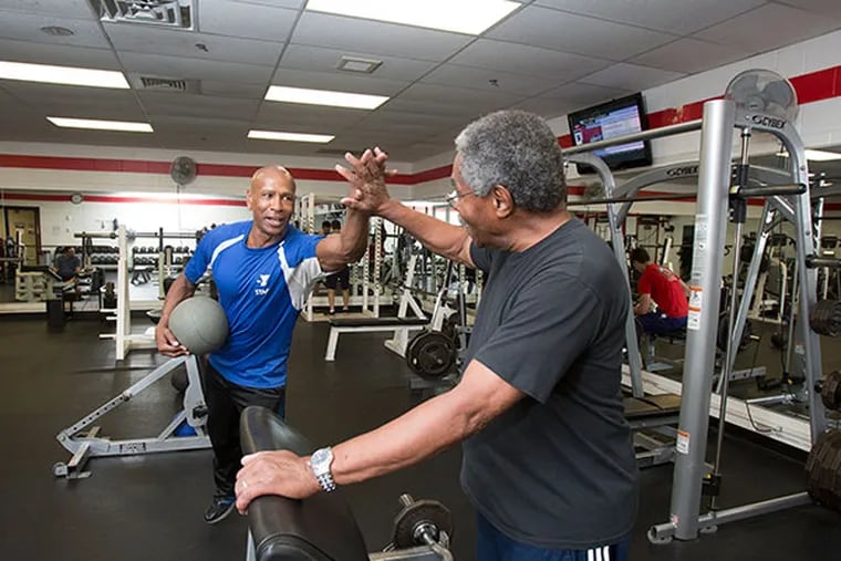 Longtime YMCA member Ed Armstead, 80, of Moorestown gets a high five from trainer Frank Budd, left, in the weight room of the Burlington County YMCA. ( ED HILLE / Staff Photographer )