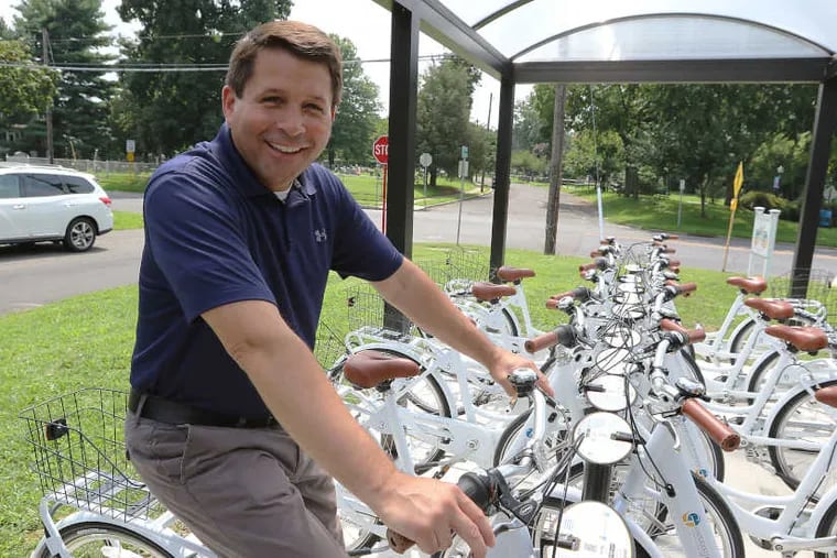 Gloucester Twp Mayor David Mayer sits on a bike at the Gloucester Township Bike Share Kiosk at West Church and Railroad Avenues in Blackwood, N.J.