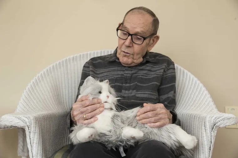 Stanley Ellis, one of the residents at Abramson Center for Jewish Life, interacts with a robotic cat. It purrs and meows when stroked.