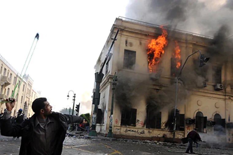 A protester uses a sling as a building burns during clashes near Tahrir Square in Cairo between soldiers and demonstrators. (Ahmad Hammad / Associated Press)