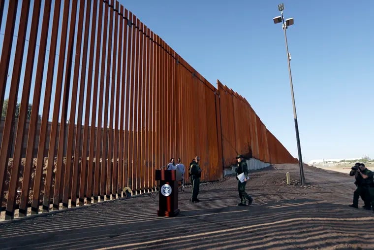 Patrol agents stand next to a new stretch of border wall in Calexico, Calif., in October.