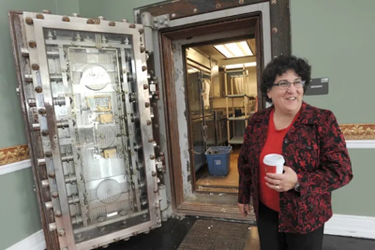 Elizabeth Dinice, who will run the culinary-arts center, stands in front of the old bank vault that contains a workstation where students will prepare dishes to be served. (April Saul / Staff Photographer)
