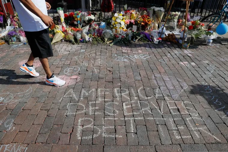 A pedestrian passes a makeshift memorial for the slain and injured victims of a mass shooting that occurred in the Oregon District early Sunday morning, Wednesday, Aug. 7, 2019, in Dayton, Ohio.  Twenty-four-year-old Connor Betts opened fire in Dayton early Sunday, killing several people including his sister, before officers fatally shot him.