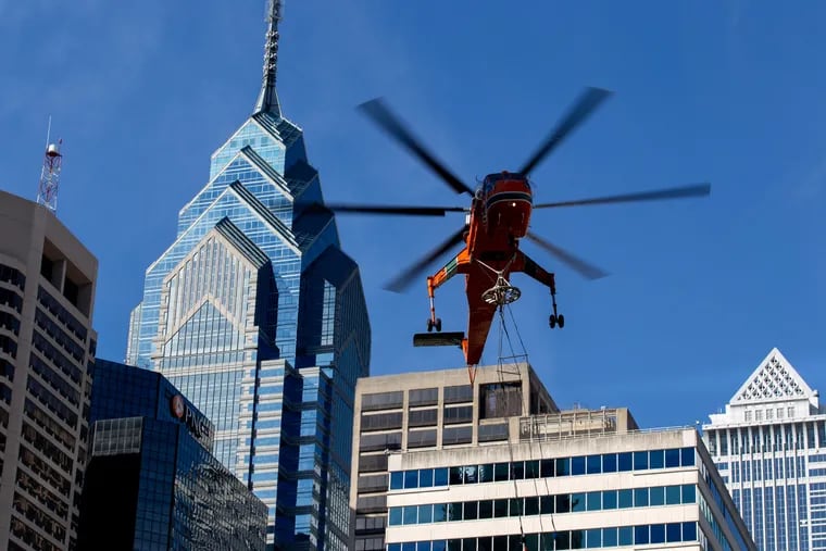 A helicopter flies over Center City, Philadelphia, while moving HVAC units to 2000 Market St.