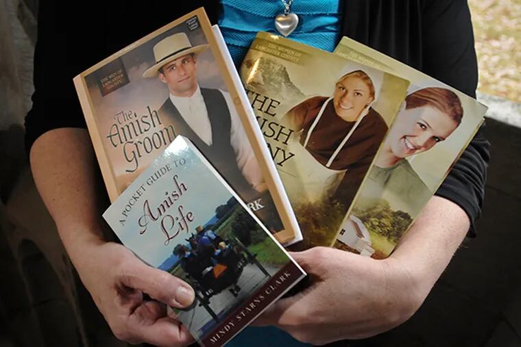 Mindy Starns Clark, a Montgomery County writer, has carved out an interesting niche: Bonnet fiction, or novels about Amish romance. Here, she holds a few of her novels. (Ron Tarver / Staff Photographer)