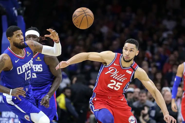 The Sixers' Ben Simmons and the Clippers' Paul George  go after a loose ball in Tuesday's game at the Wells Fargo Center.