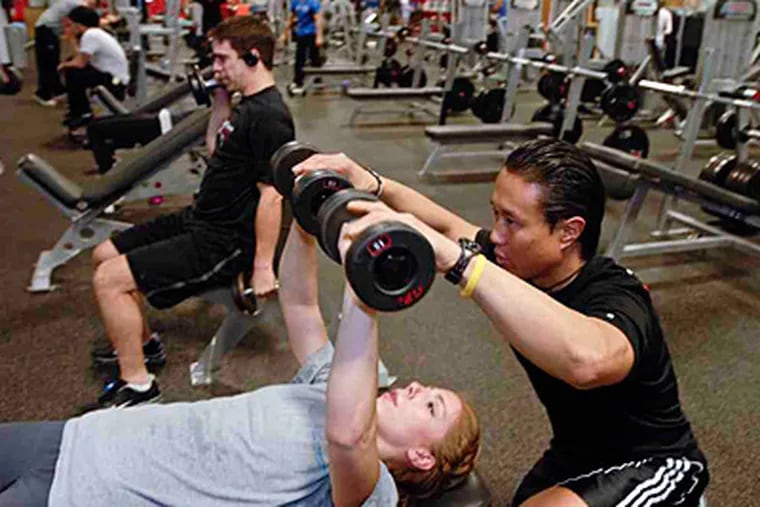 Tony Kim, a personal trainer at City Fitness on Spring Garden, helps Tiffany Buchert of Northern Liberties with her workout. (Ron Tarver/Staff)